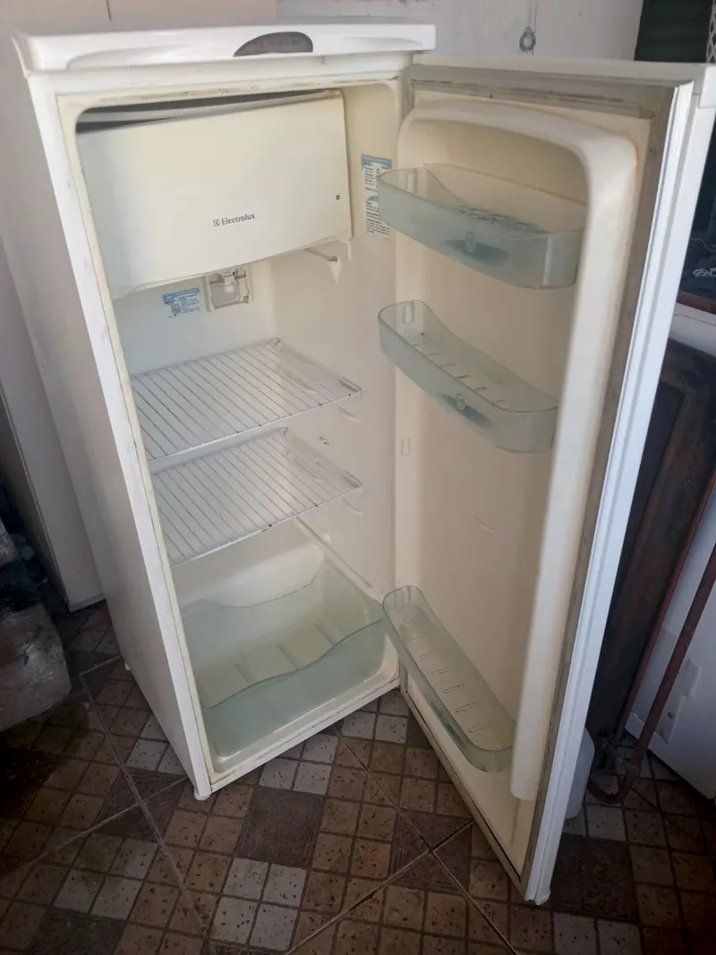 Geladeira branca de uma porta, aberta, com as prateleiras da porta