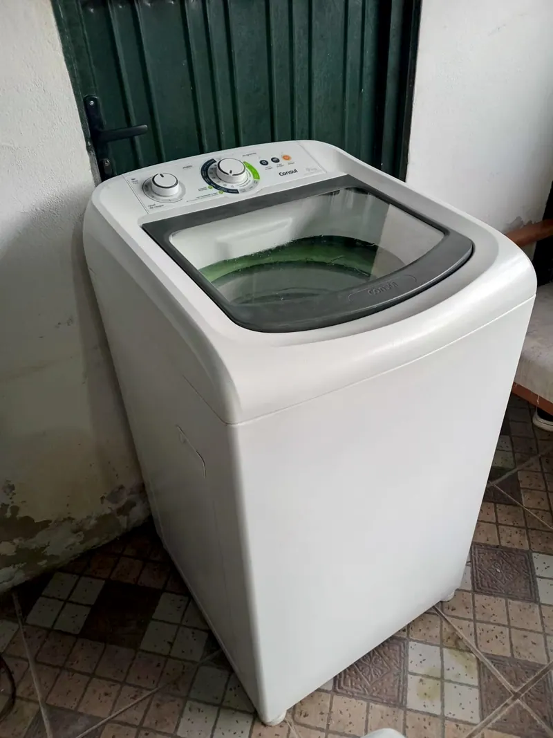 Lavadora branca vista de lado, no pátio de lajotas